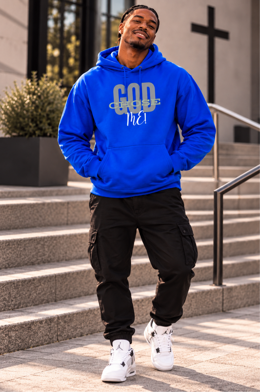 A man wearing a bright blue hoodie with 'GOD CROS! Me!' printed on the front, paired with black cargo pants and white sneakers, standing on outdoor stone steps in front of a church building.